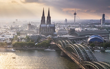 Köln: Luftaufnahme Kölns mit Dom, Rhein und Hohenzollernbrücke bei warmer Abendsonne über der Altstadt.