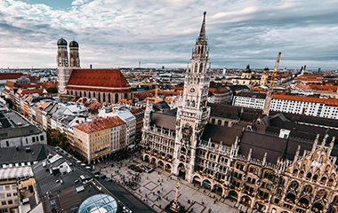 München: Luftaufnahme Münchens mit Marienplatz, Frauenkirche und Rathaus bei dramatischem Himmel über der historischen Altstadt mit roten Dächern.
