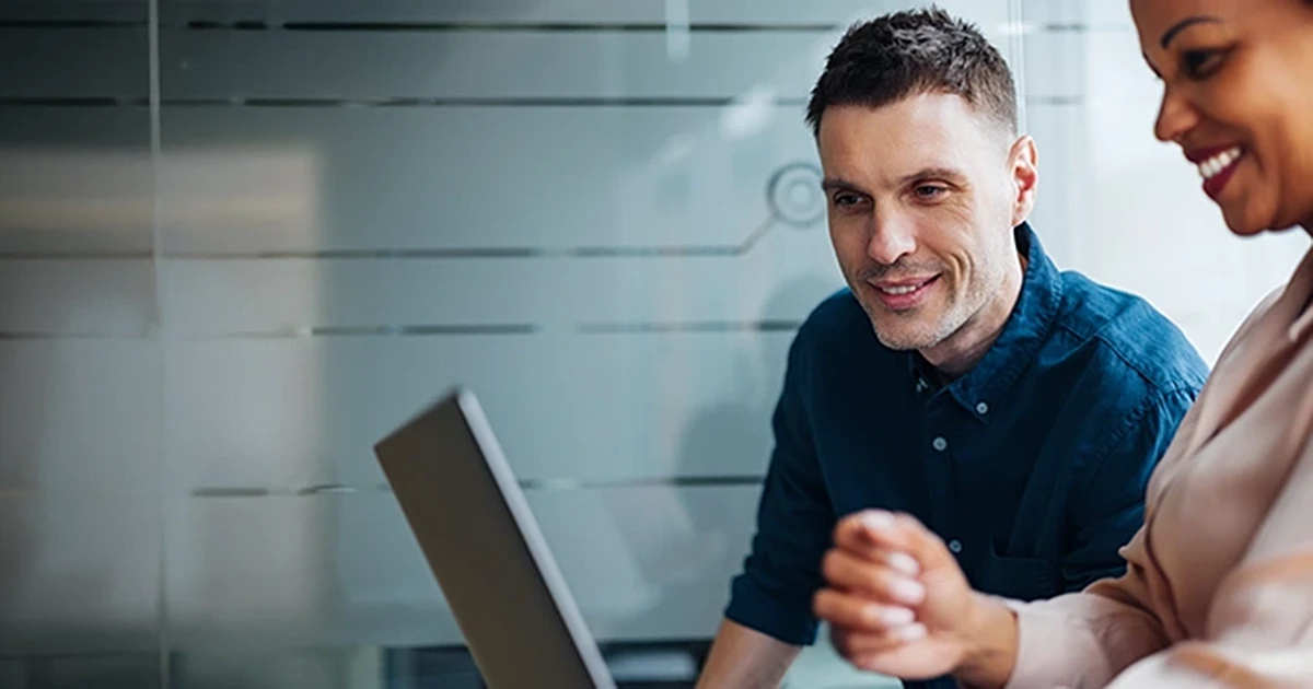 einkauf-kuenstliche-intelligenz-junger-mann-vor-pc-Beitrag Professioneller Mitarbeiter bespricht freundlich KI-Lösungen mit Fachkraft vor Laptop im Unternehmen. KI im Einkauf