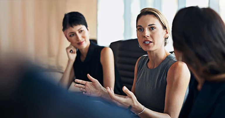 Professionelle Businessfrau kommuniziert aktiv in Teambesprechung, moderne Büroatmosphäre. Erstmals Führungskraft