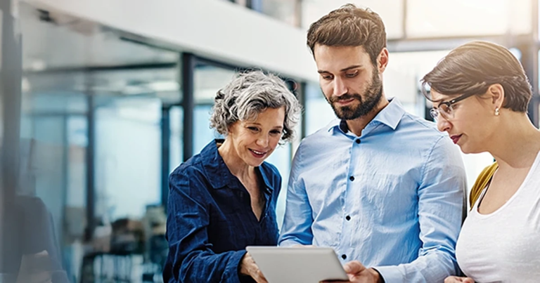 Fokussierte Teamarbeit am Arbeitsplatz, drei Kollegen schauen konzentriert auf ein Tablet. Zeitmanagement und Selbstmanagement