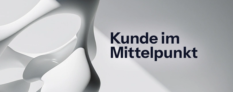 Abstrakte 3D-Skulptur auf hellem Hintergrund mit dem schwarzen Schriftzug „Kunde im Mittelpunkt". Customer Centricity
